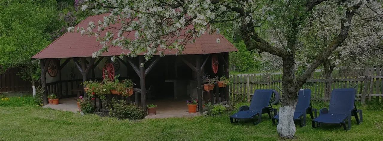 Contactează Pensiunea Casa Iulian pentru o rezervare: imagine cu foișorul din grădina înverzită, un loc perfect de relaxare în vacanța ta la munte.